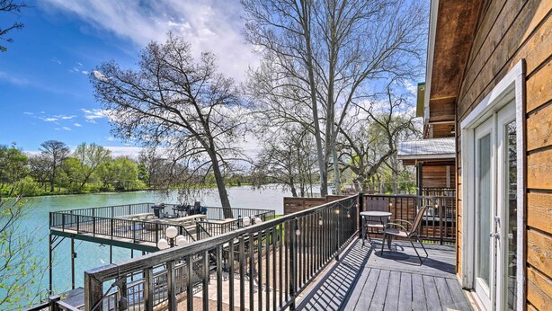 Una terraza de madera con mobiliario exterior con vista a un lago.