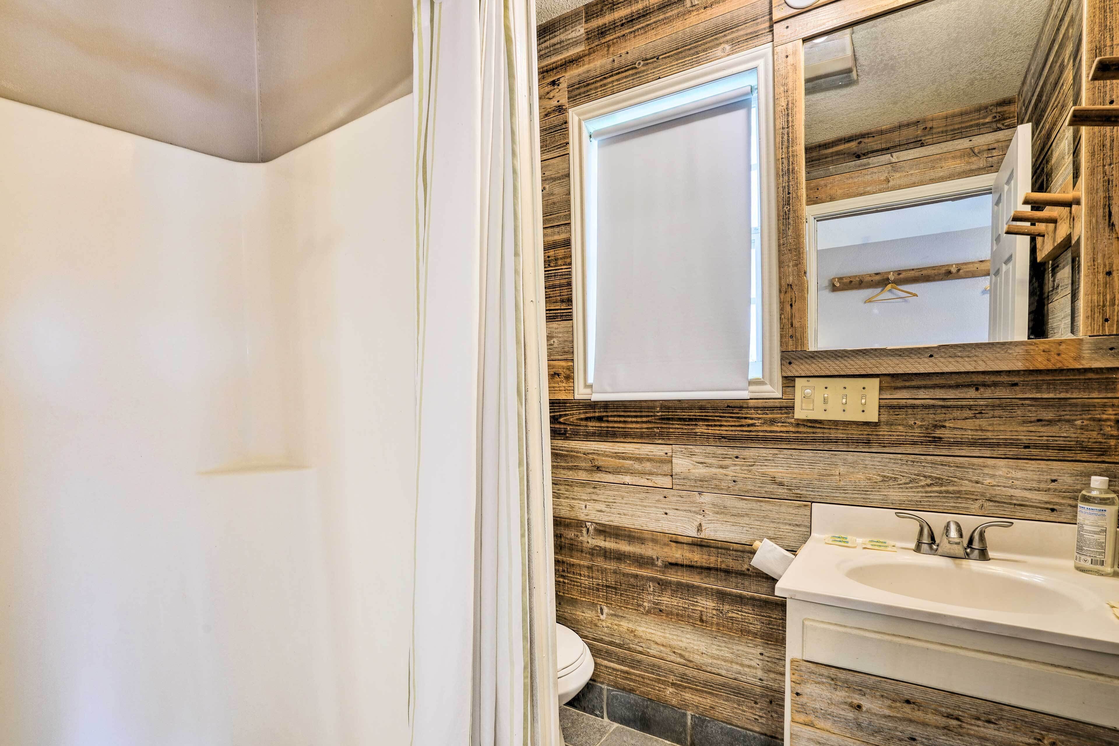 A bathroom with a wooden wall, a white sink, and a mirror.