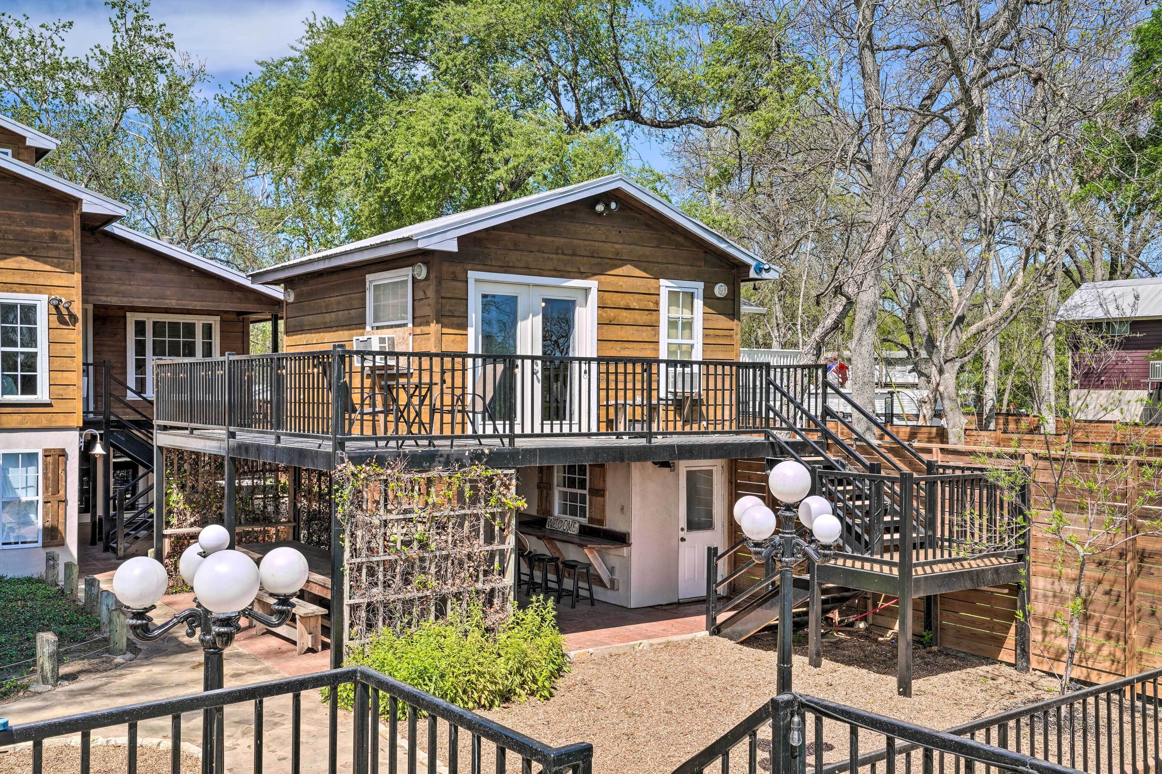 A wooden cabin with a balcony, a small deck, and a staircase leading to the upper level.
