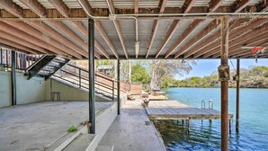 Un muelle de hormigón que se adentra en una masa de agua tranquila, con un embarcadero de madera y una escalera que baja hacia el agua.