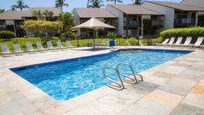 Ein Swimmingpool mit Fliesenrand, Liegestühlen und einer Person in einem blauen Hemd.