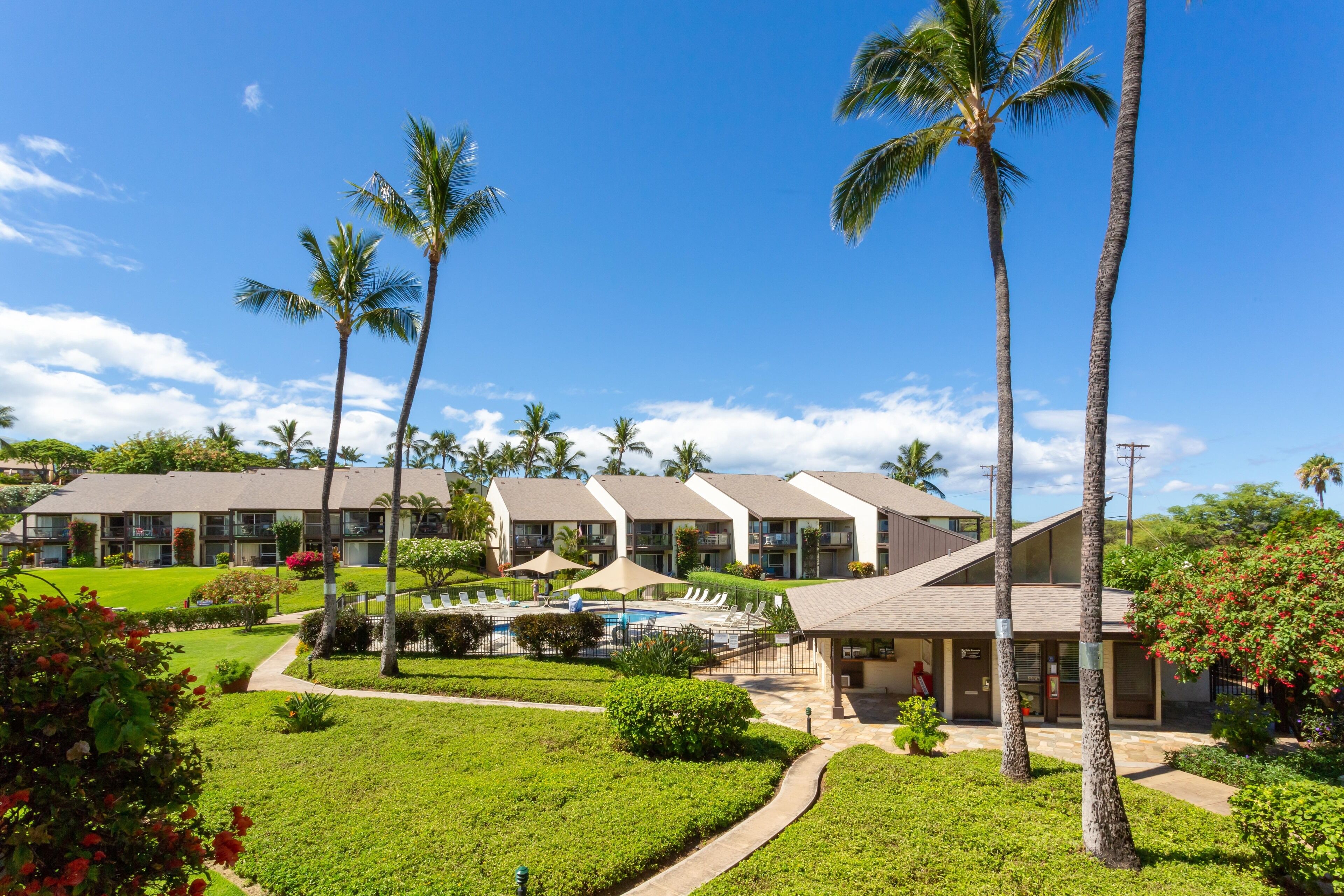 A resort with multiple buildings, a swimming pool, and well-maintained gardens.