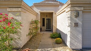 A two-story house with a beige exterior, a front door, and a garage door. - Cave Creek Beauty with Sunset and Golf Course Views! (Cave Creek)