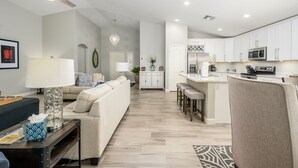 A modern kitchen with white cabinets, a microwave, and a coffee maker. There is a dining area with a table and chairs. - Cave Creek Beauty with Sunset and Golf Course Views! (Cave Creek)