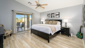A bedroom with a bed, a ceiling fan, a nightstand, a lamp, and a guitar. - Cave Creek Beauty with Sunset and Golf Course Views! (Cave Creek)