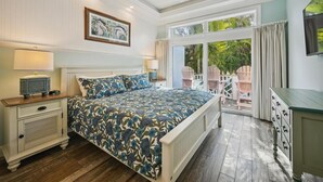 Un dormitorio con una cama grande, una mesita de noche, un aparador, un ventilador de techo y una ventana con vistas al exterior.