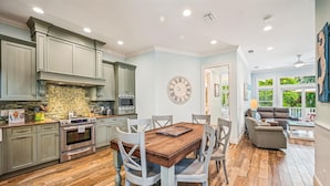 Una cocina amplia con electrodomésticos modernos, un comedor con mesa de madera y una sala de estar con un ventanal grande.