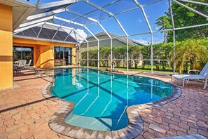 A swimming pool with a glass enclosure, surrounded by a brick patio and outdoor furniture. - Naples Home w/ Pool, Extended Stays Welcome! (Naples)