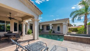 Un espace aménagé au bord de la piscine, comprenant un ensemble de mobilier de jardin et des chaises longues, une terrasse couverte avec des colonnes, et une vue sur la piscine.
