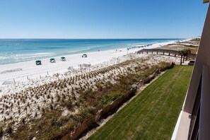 A beach view with a clear sky, a sandy beach, and a few umbrellas.