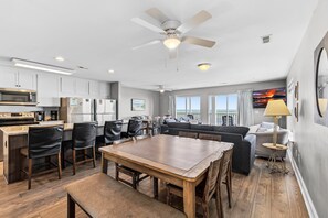 Una cocina moderna con comedor, una sala de estar con sofá y televisor, y un balcón con vistas.