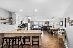 Una cocina moderna con una isla central, taburetes de bar y una zona de comedor con mesa y sillas.