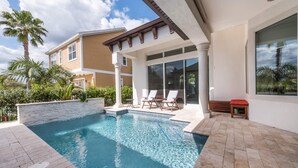 Ein modernes Haus mit Swimmingpool, einer Terrasse mit Liegestühlen und einem großen Fenster mit Blick auf den Pool.