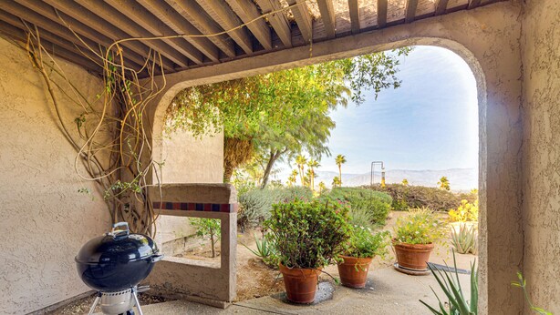 Un patio al aire libre con una parrilla, plantas en macetas y vistas del paisaje.