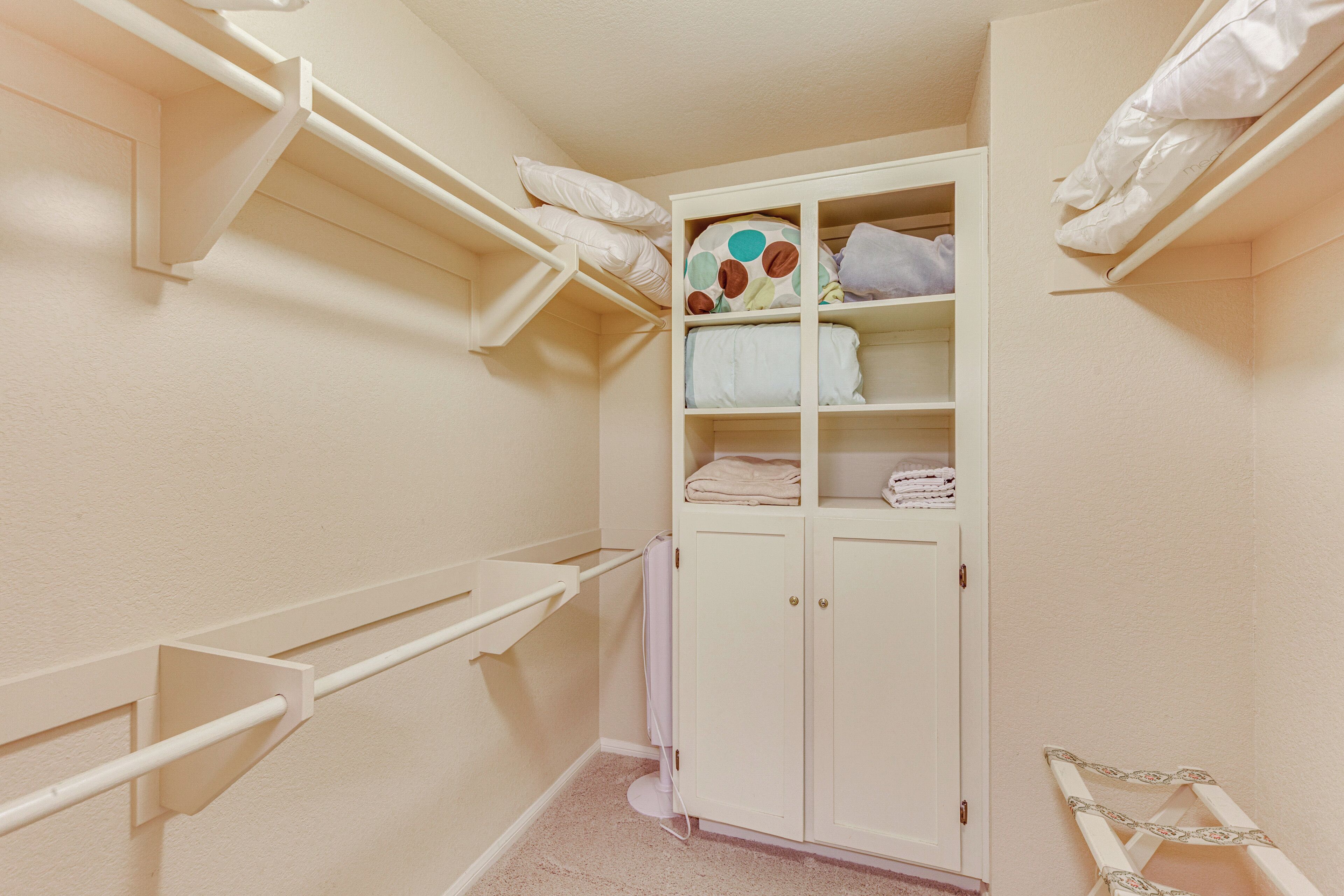 A small, well-organized closet with shelves, a hanging rack, and a cabinet.