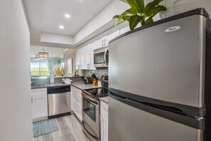 Eine moderne Küche mit Edelstahlgeräten, weißen Schränken und einem großen Kühlschrank.