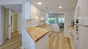 Une cuisine moderne avec des meubles blancs, des plans de travail en bois et un îlot central.