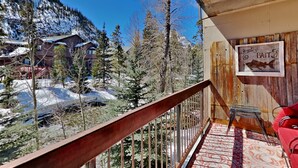 A balcony with a view of snow-covered mountains and trees, a wooden railing, and a sign that reads "Fresh Bait." - Creekside Condo in Downtown Frisco with Hot Tub, Pool & Mountain Views! (Frisco)