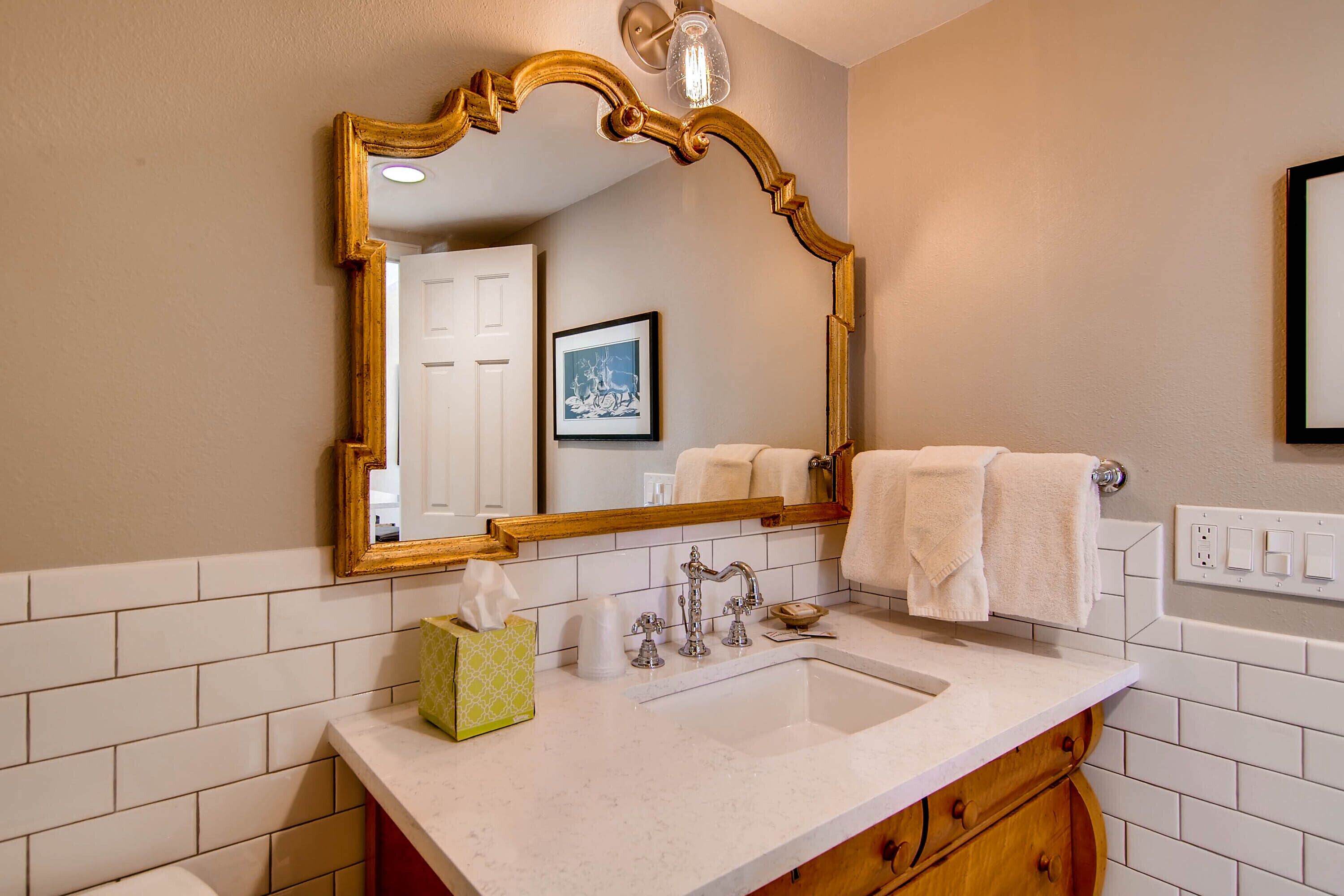 A bathroom with a large mirror, a sink, and a towel rack.