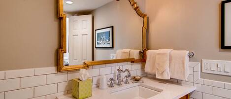 A bathroom with a large mirror, a sink, and a towel rack.