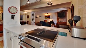 A modern kitchen with a stainless steel range hood, a built-in toaster, and a dining area with a red chair and a table. - Creekside Condo in Downtown Frisco with Hot Tub, Pool & Mountain Views! (Frisco)