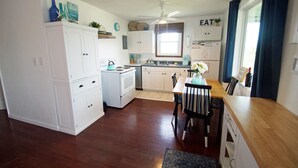 Una cucina compatta con mobili bianchi, un tavolo da pranzo in legno e una ventola a soffitto.