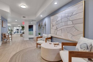 A modern interior with a round wooden table, seating area, and a large abstract painting on the wall.