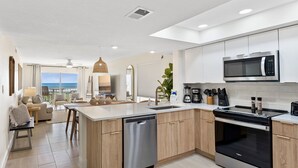 Una cucina moderna con lavastoviglie, forno e microonde. Dispone di una grande isola con lavello e vista sull'oceano attraverso ampie finestre.