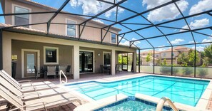 Piscina coberta ao ar livre com espreguiçadeiras, mesa e área de pátio.