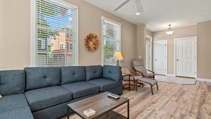 Una sala de estar con un sofá modular, dos sillones, una mesita de centro y un ventilador de techo.