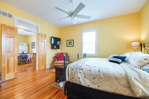 Une chambre à coucher avec un lit, un ventilateur de plafond, une télévision et une fenêtre.
