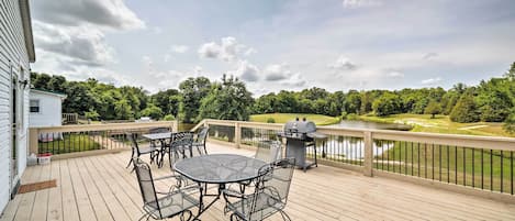 Una terraza con mobiliario exterior, una parrilla y vistas a un campo de golf y un lago.