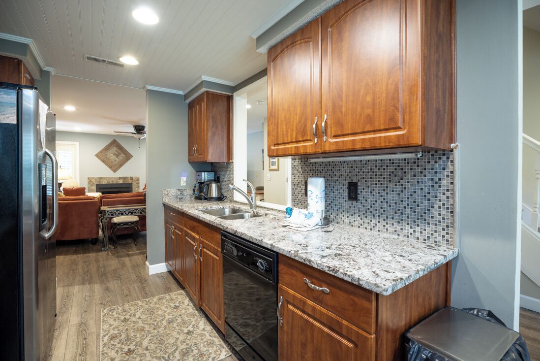 A kitchen with wooden cabinets, granite countertops, and a dishwasher.