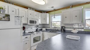Une cuisine moderne avec des meubles blancs, un plan de travail en granit, un four à micro-ondes, une cuisinière et un évier.