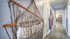 Un couloir orné d’une décoration murale en macramé et d’une autre décoration murale en macramé avec un sac suspendu.