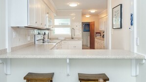 Una cocina moderna con armarios blancos, una isla grande y vista al área de comedor contigua.