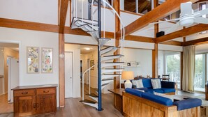 Un amplio salón con un banco de madera, un sofá azul y una escalera de caracol.