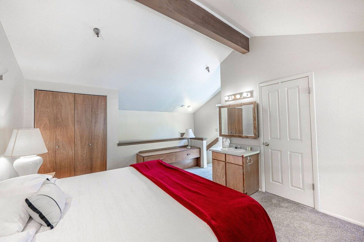 Ein Hotelzimmer mit einem Bett, einem Schminktisch mit Spiegel, einem Holzschrank und einer Tür.