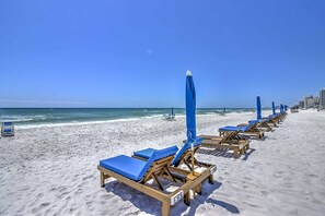 A beach with rows of sun loungers and umbrellas, a clear sky, and the ocean in the background. - Seaside Panama City Beach Condo w/ Outdoor Pool! (Panama City Beach)