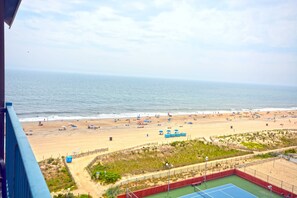 A beach with a tennis court and a view of the ocean.