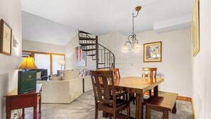 Een eethoek met een houten tafel en stoelen, een trap en een kroonluchter.