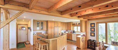 A spacious kitchen with wooden cabinetry, a large island with stools, and a dining area with a table and chairs.