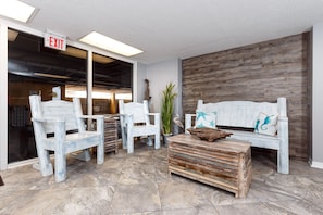 A lobby with white chairs, a wooden bench, and a sign indicating an exit.