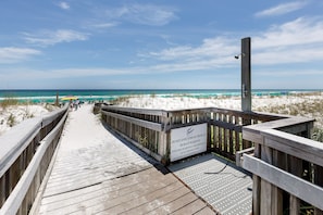 Une promenade en bois mène à une plage où un panneau indique qu’il est interdit de laisser des objets sur le sable.