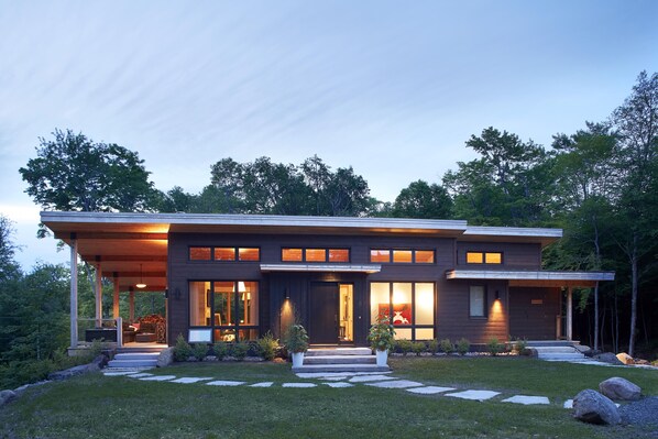 A modern two-story house with a covered porch, large windows, and a well-maintained lawn.