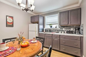 Una cucina moderna con mobili grigi, un piano di lavoro in marmo e una zona pranzo con tavolo e sedie in legno.