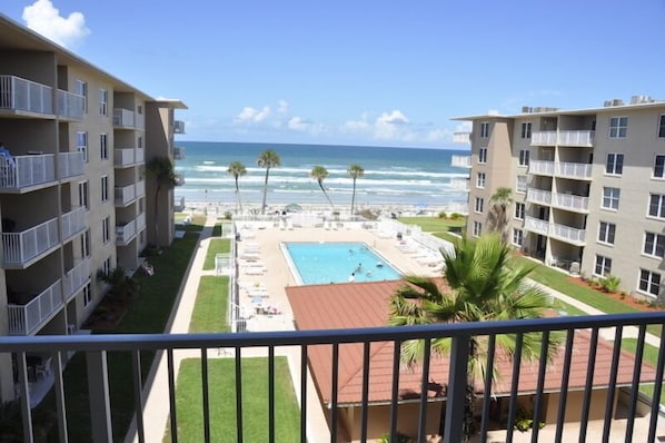 A hotel with a pool, beach view, and balconies.