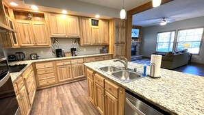 A spacious kitchen with wooden cabinets, granite countertops, and stainless steel appliances. - Greenway Crossing @ Spring Brook Resort (Wisconsin Dells)