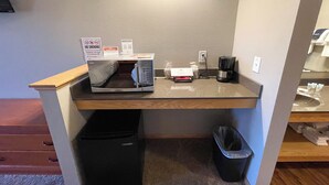 Une petite cuisine équipée d’un four à micro-ondes, d’une machine à café et d’une poubelle.