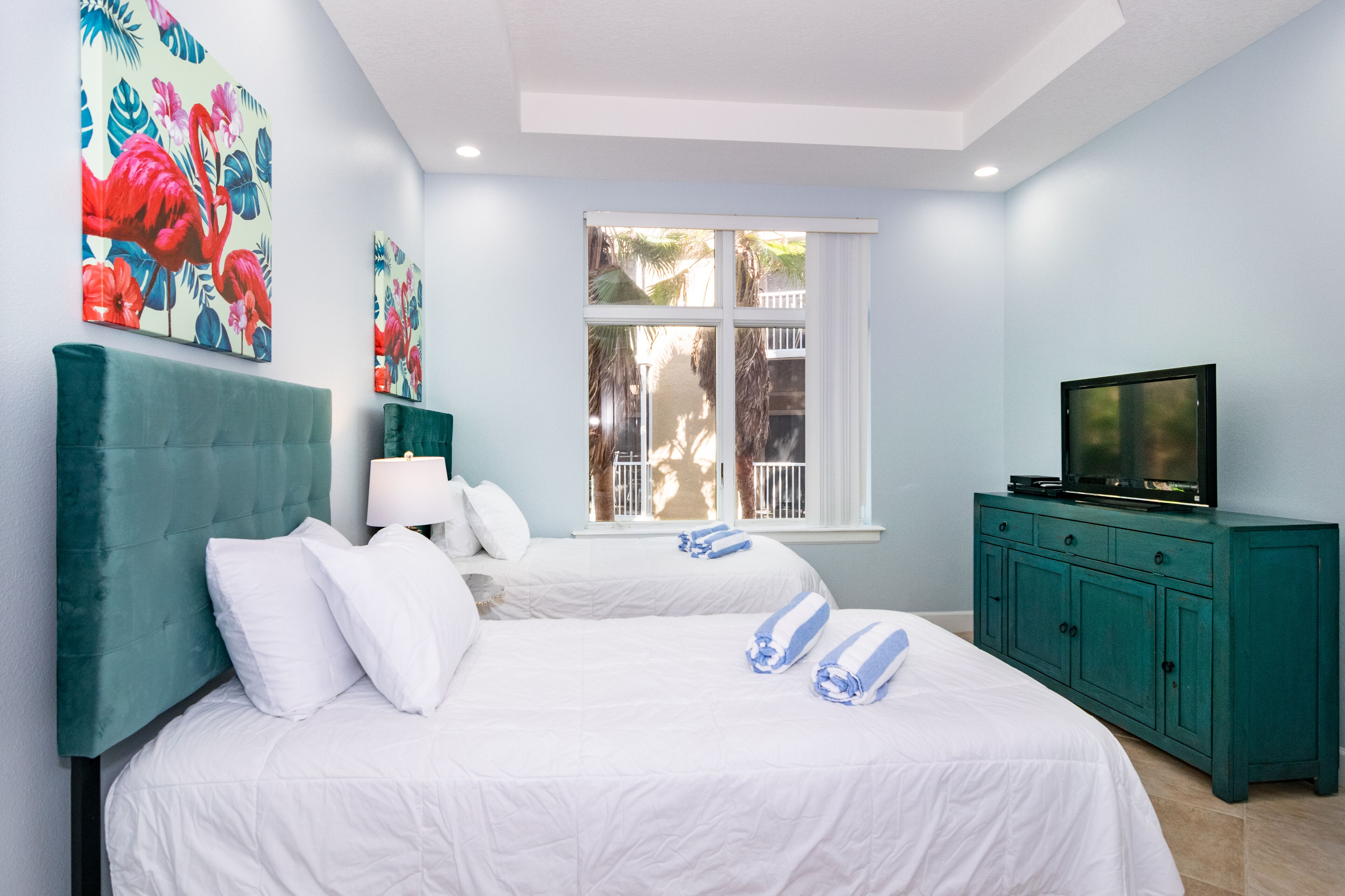 Habitación de hotel con dos camas, un televisor y obras de arte en la pared.